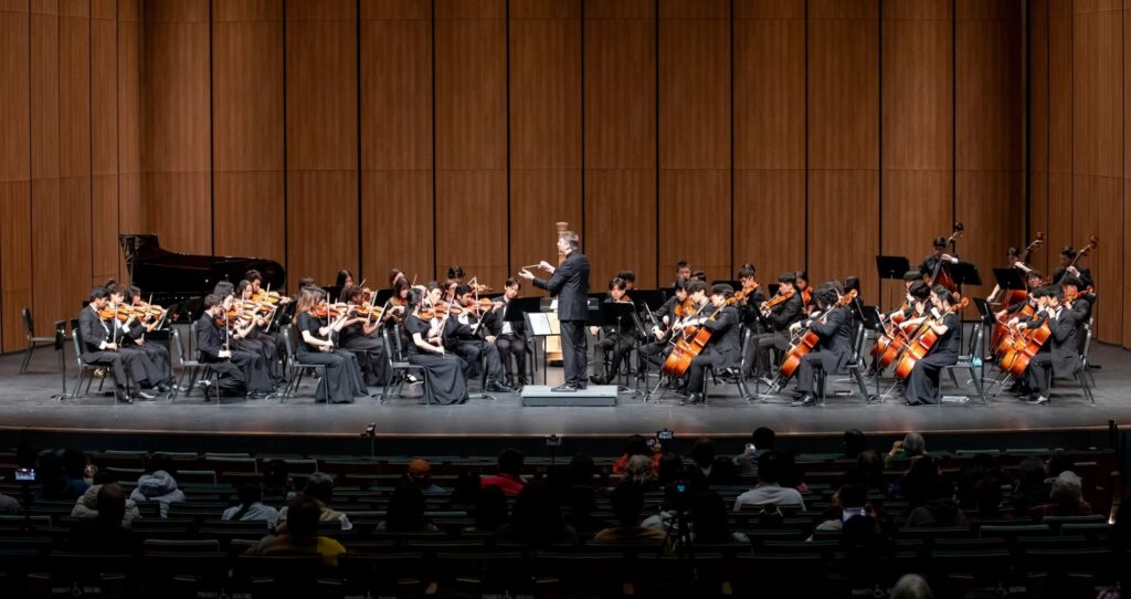 Ryan conducting the Plano West string orchestra on the TMEA convention stage at the Lila Cockrell Theatre